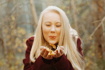a woman blowing leaves out of her hands 