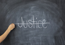 crossing through the word Justice on a chalkboard 