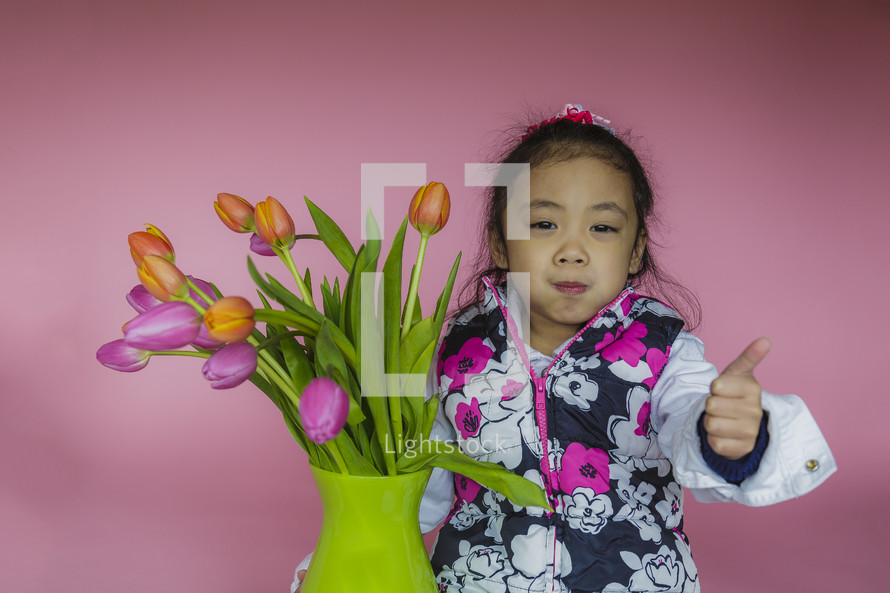 girl child with colorful tulips in a vase 