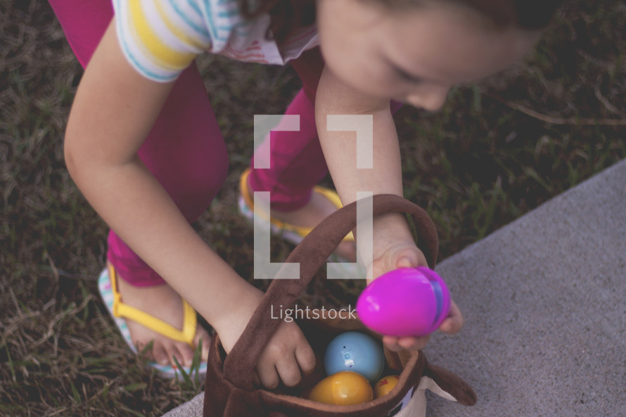 girl putting Easter eggs in an Easter basket 