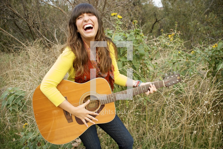 woman laughing playing a guitar 