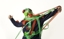 Man tangled in red and green ribbon with bowc stuck to his body and head.