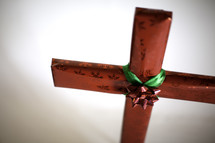 Red wrapped present shaped like a cross with red and green bow in the center.