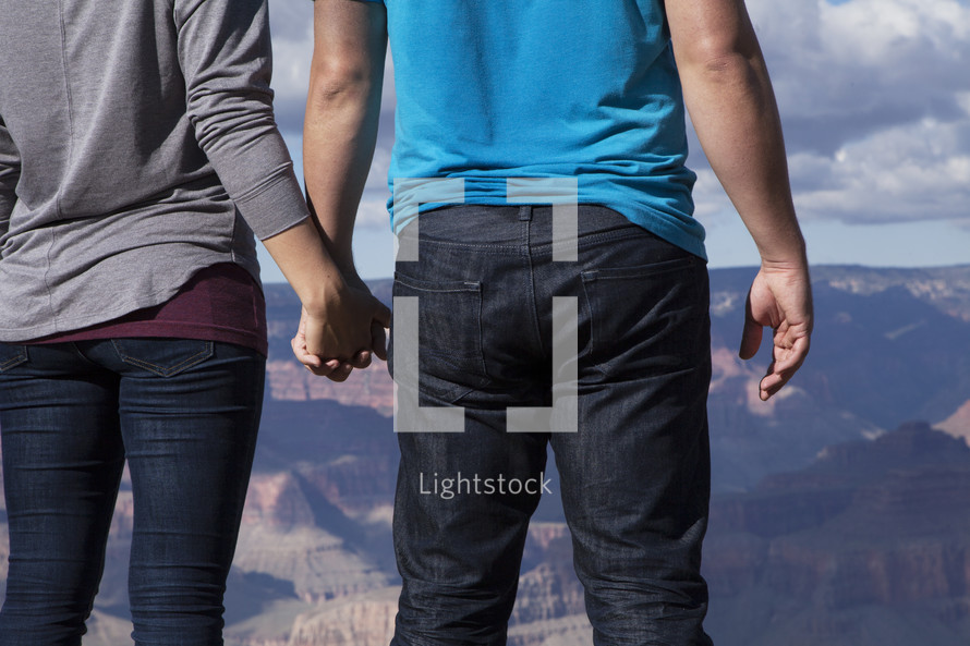 a couple holding hands at the top of a canyon