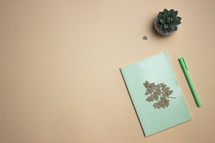 Diary concept with green pen and leaves on a brown background. 