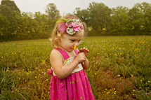 toddler girl in a field smelling a dandy lion flower
