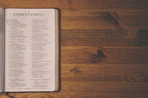 Bible on a wooden table open to the book of Lamentations.