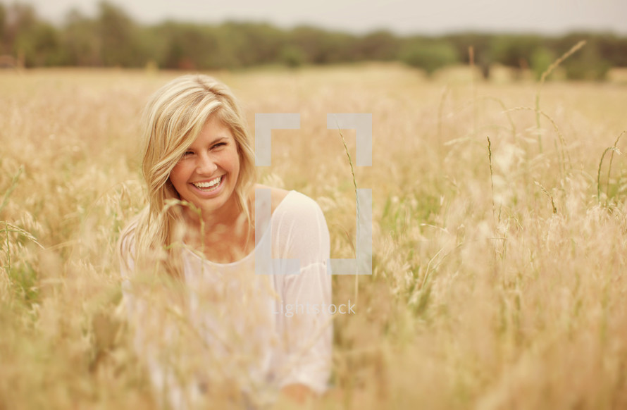 smiling woman in the tall grass in a field