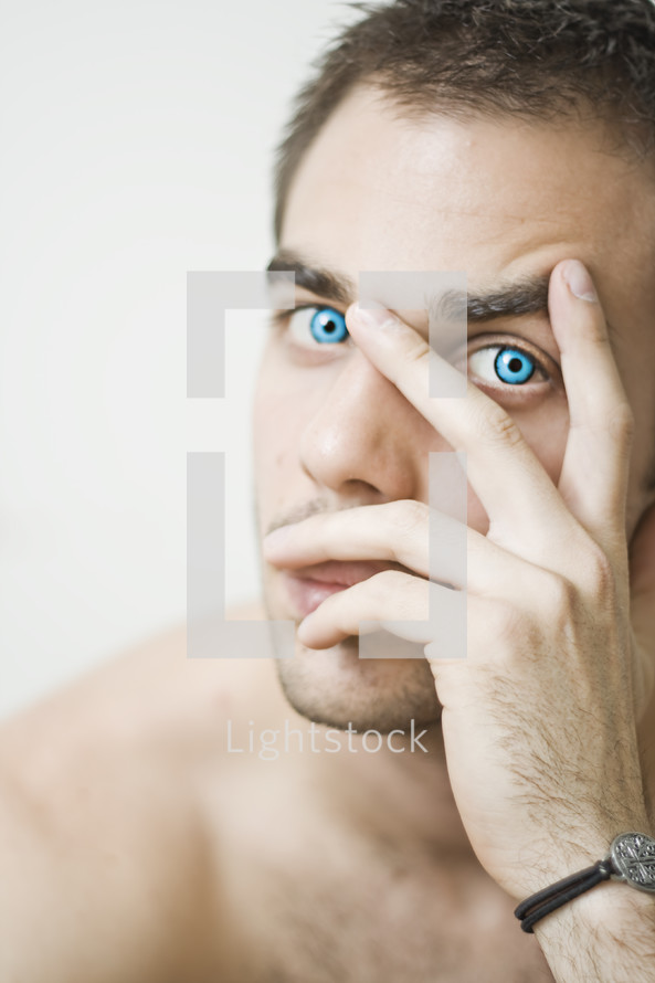 man with brilliant blue eyes peeking through his fingers