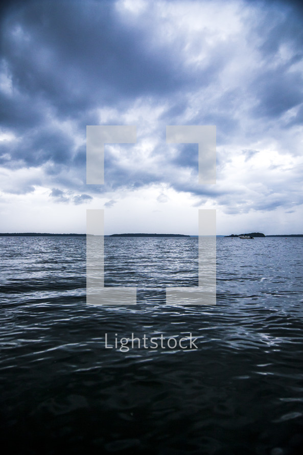 Boats on the ocean water under a stormy sky.