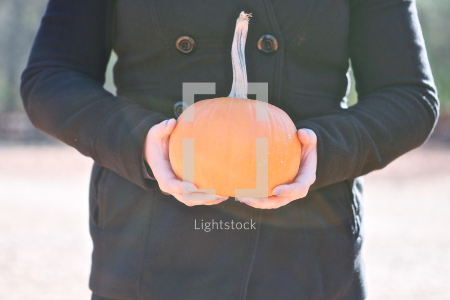 torso of a woman holding a pumpkin