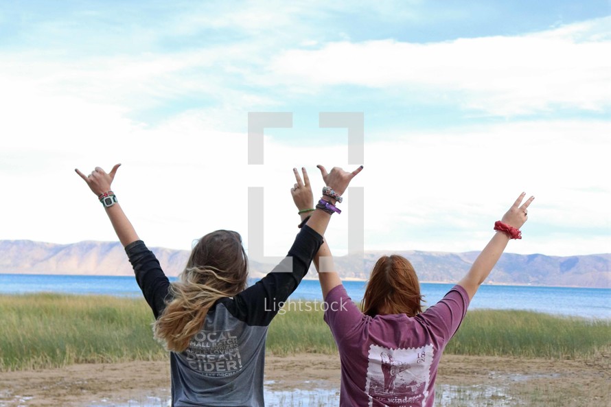 girls with hands raised outdoors 