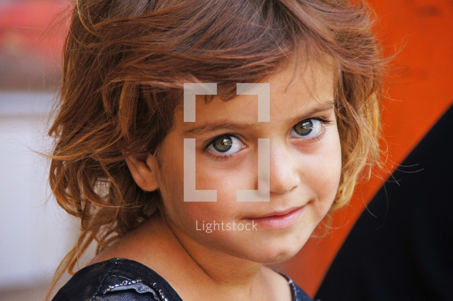 Kurdish Girl with big eyes smiling against orange background. 
[For more like this search 'Ethnic faces' or search 'Refugees' or to see how I first met her search for image '162819']