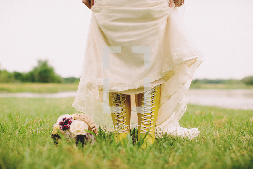 A bride pulling up her dress to show yellow lace up boots