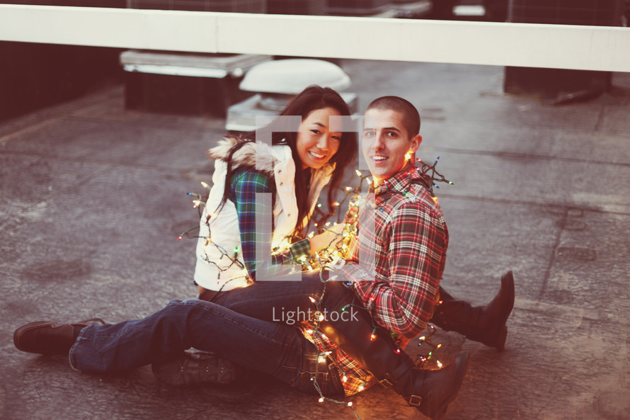 Happy couple wrapped in Christmas lights