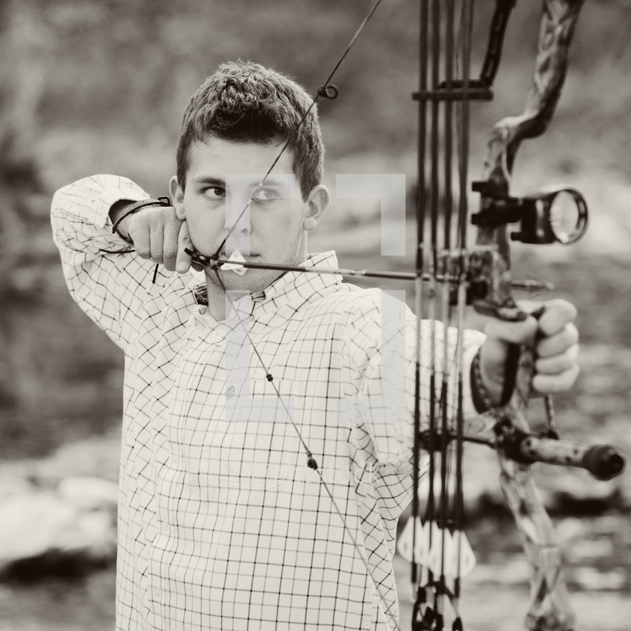 A young man shooting a bow and arrow.