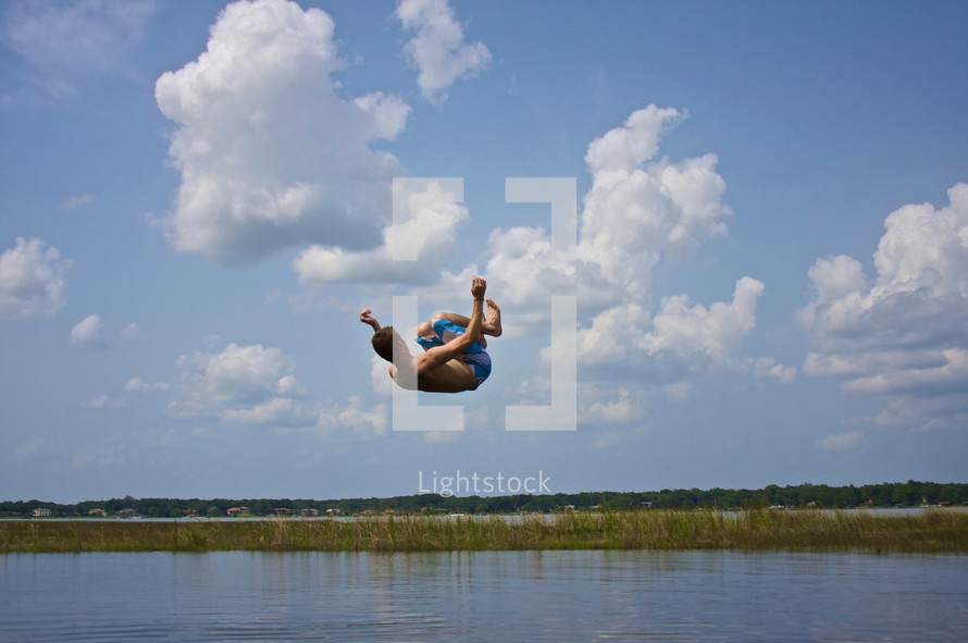 boy jumping into lake 