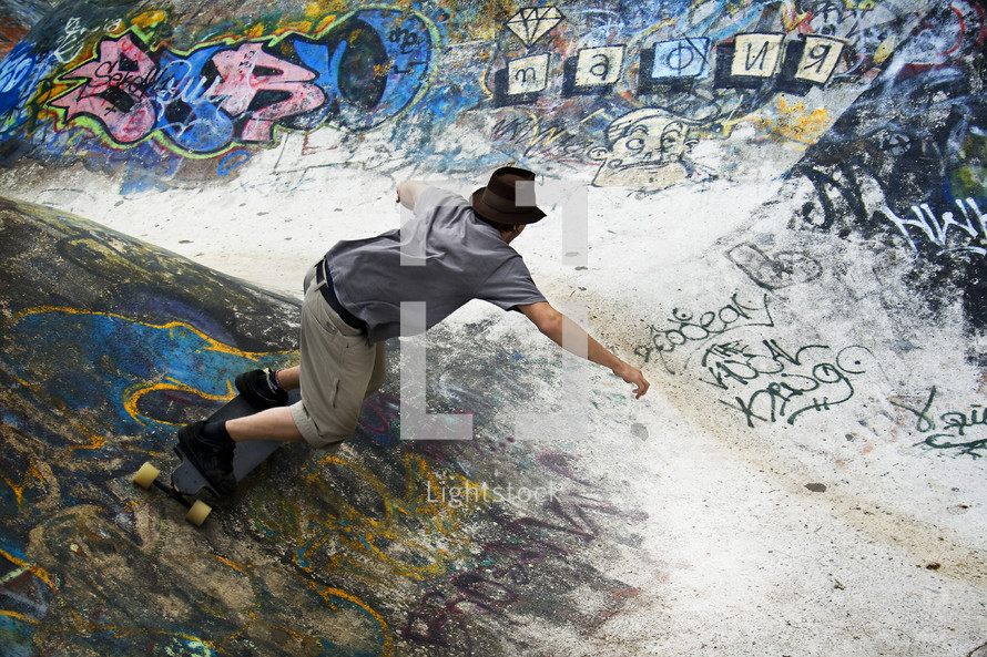 man skateboarding on a ramp at graffiti covered skateboard park