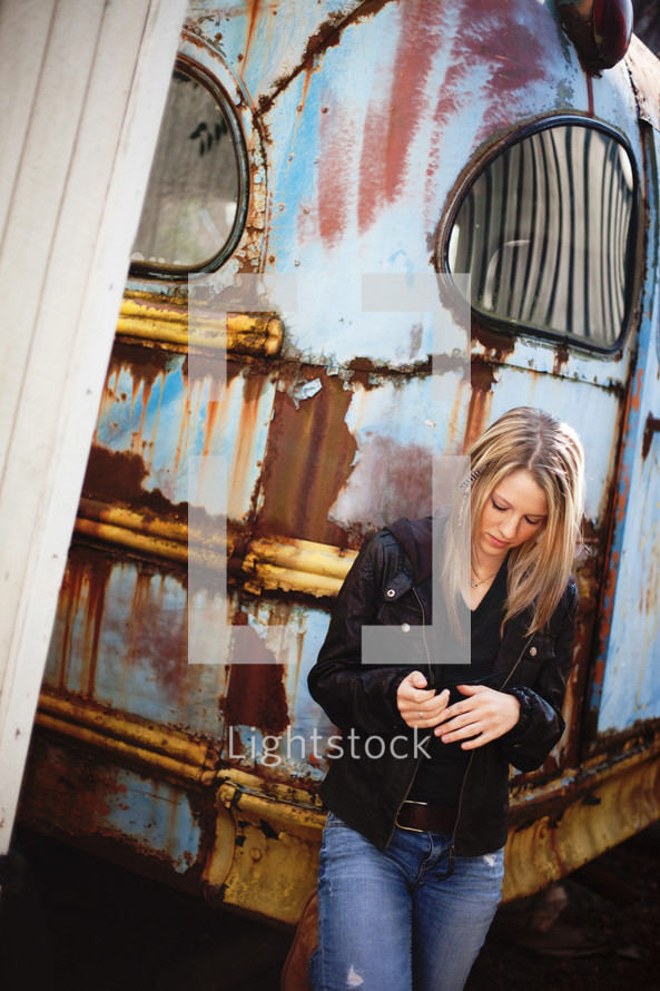 woman standing in front of an old bus looking down at her hands