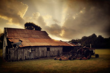 An old barn and tractor in a field.