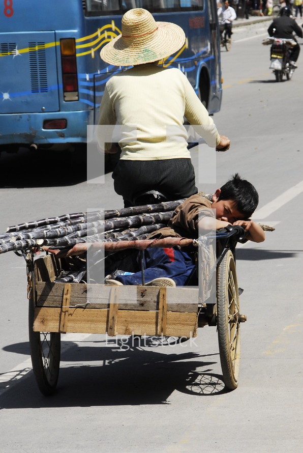 Woman - bicycle pulling wagon with boy asleep - street - Asian