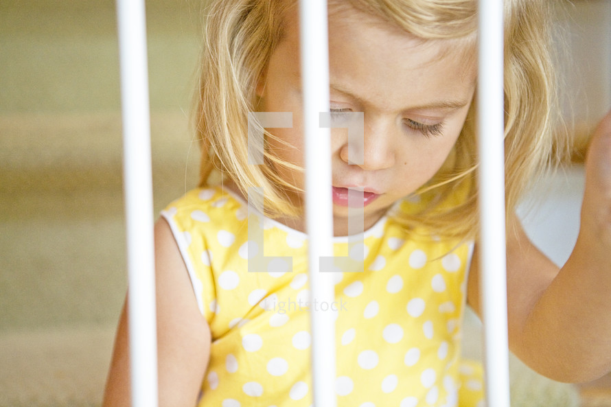toddler girl looking through bars