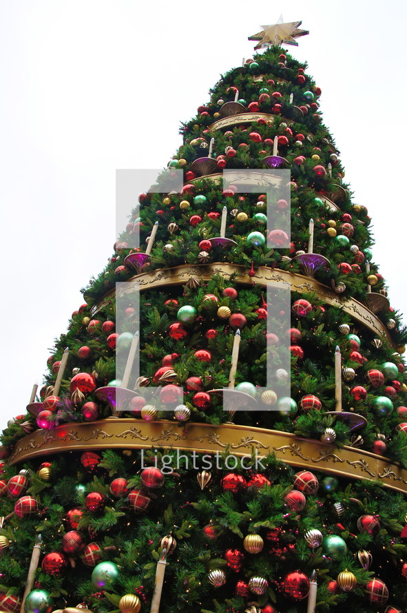Decorated Christmas tree with gold, red, purple, ball ornaments hanging from it.