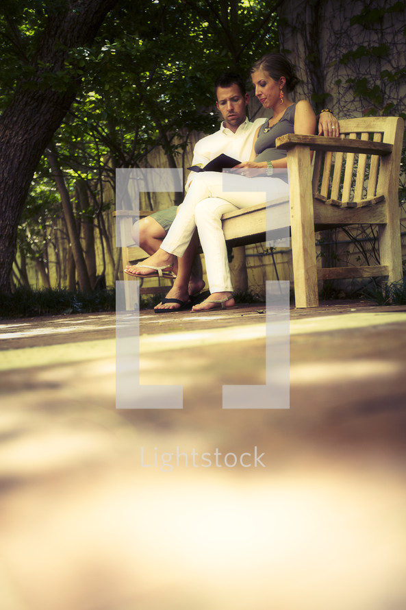 Couple reading Bible on park bench