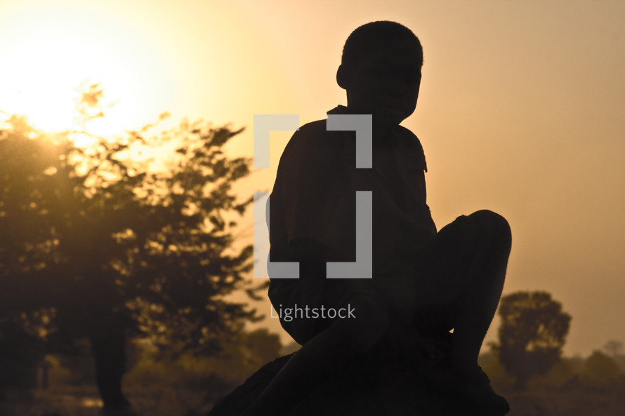 A boy sitting on a rock.