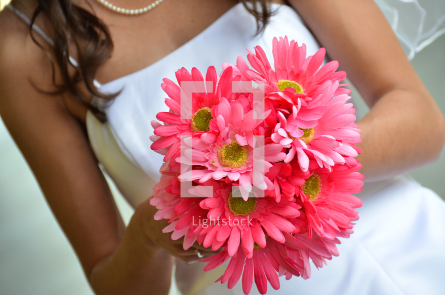 bride holding a bouquet of pink gerber daisies 