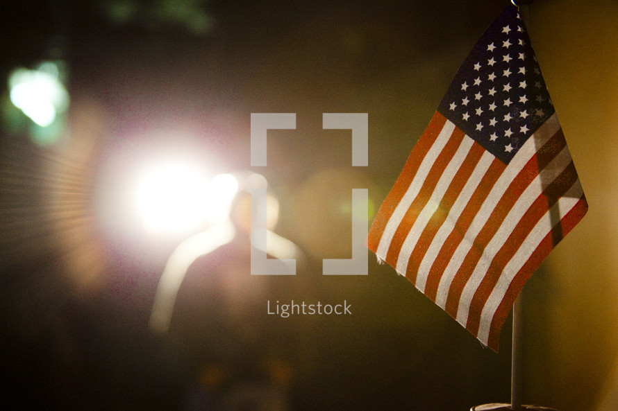 American flag with silhouette of man in lighted background.