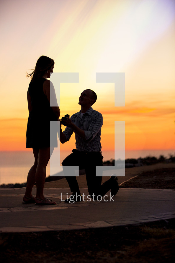 silhouette of man proposing to woman - sunset