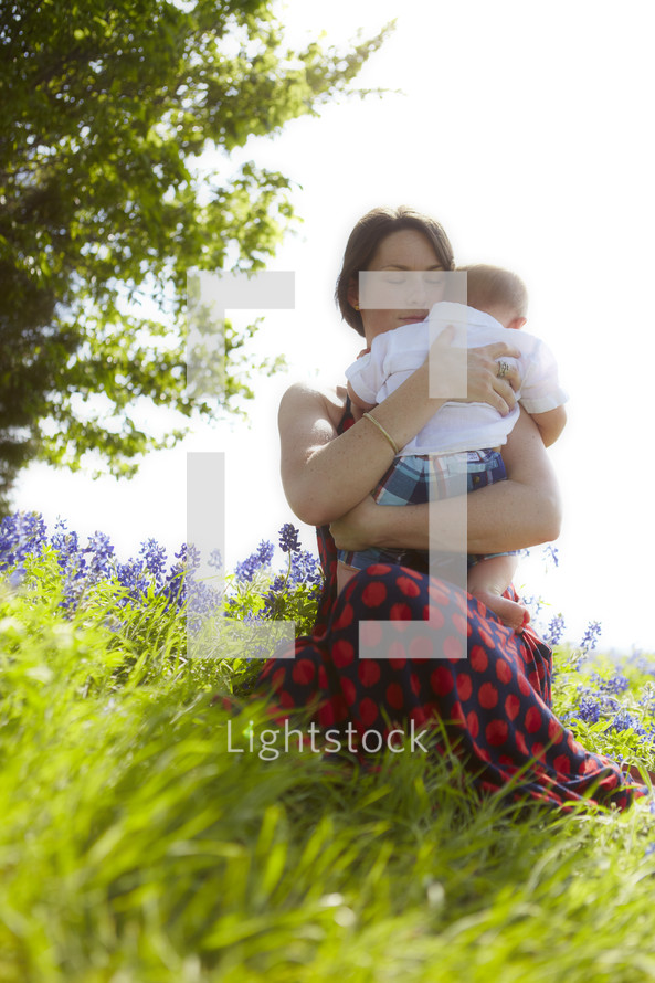 A woman holding her baby in a field of flowers