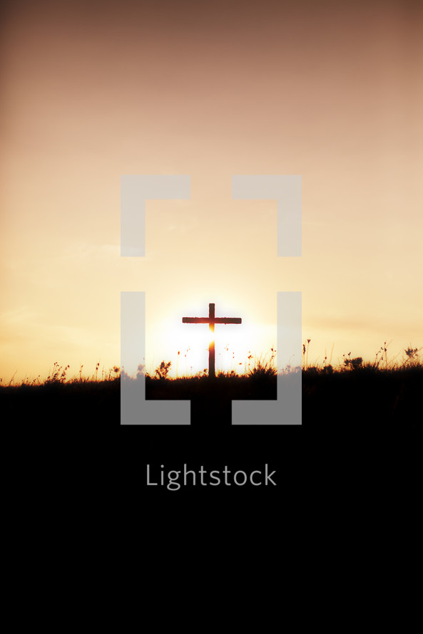 A silhouetted cross on the horizon at sunrise