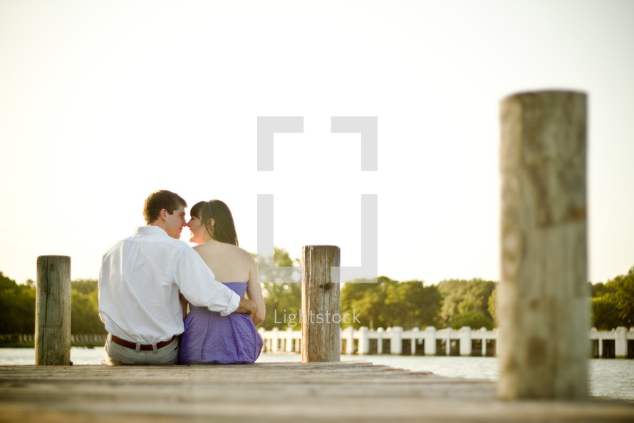 couple sitting and kissing at the end of a dock