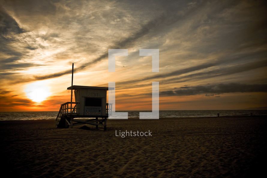 lifeguard stand on a beach at sunset