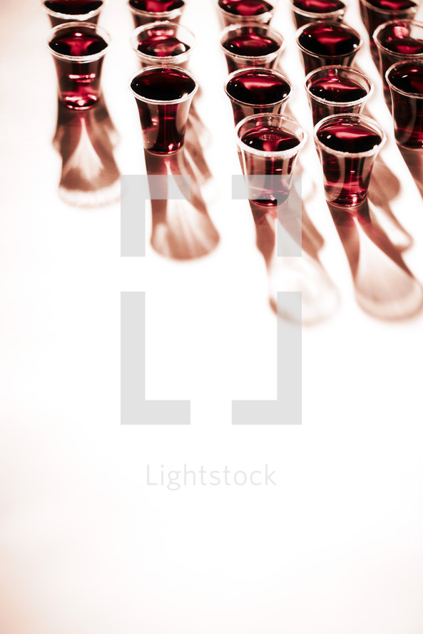 An organized group of communion cups filled with wine isolated on white