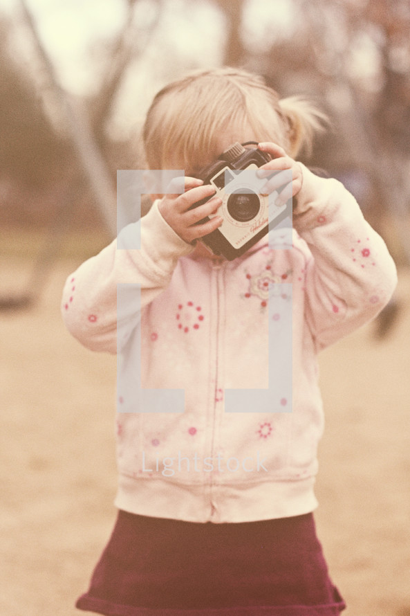A little girl looking through a camera.