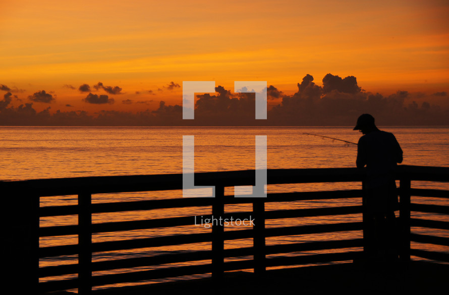 silhouette of a man fishing on a pier