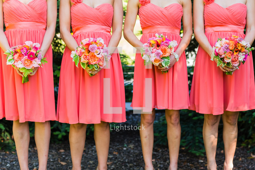 Bridesmaids in orange peach dresses with floral bouquets 