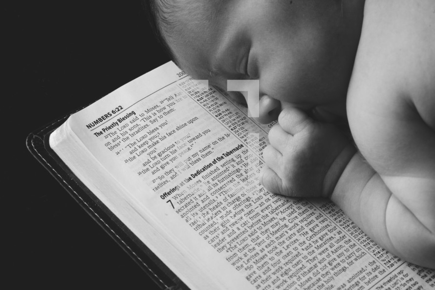 Infant sleeping on top of an open bible