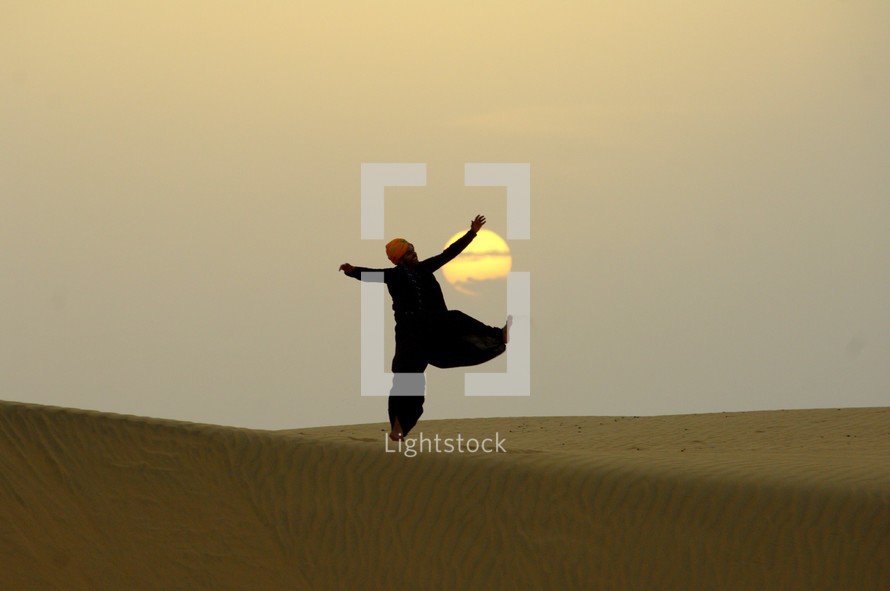man dancing in front of the setting sun in India 