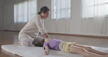 Shiatsu treatment. Masseuse giving treatment to a young girl, using different methods.