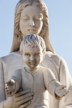 Statue of holy Virgin Mary mother of the child Jesus on blue sky.