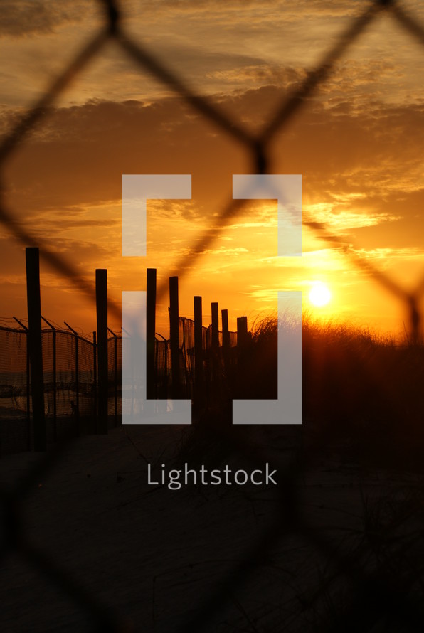 chain link fence and barbed wire at sunset 