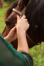 a woman adjusting reins on a horse 