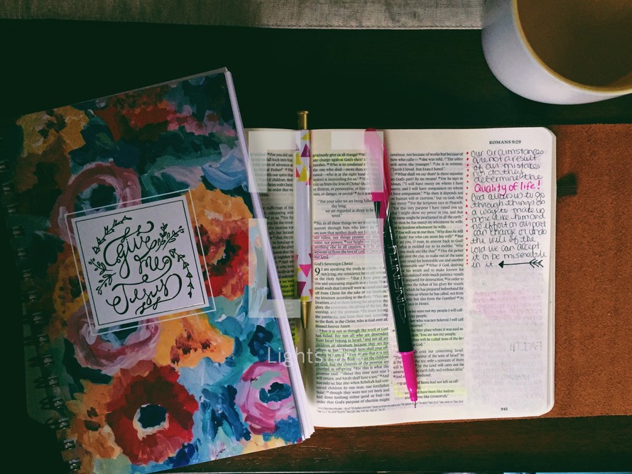 An open Bible with highlighted verses and a notebook.