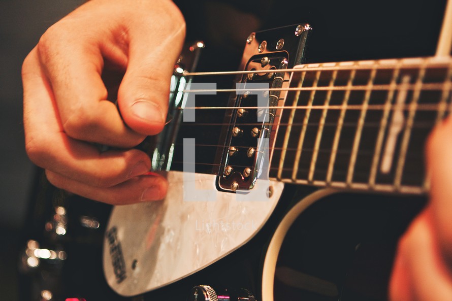 Man's hands strumming guitar.
