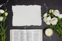 open Bible on a black marble desk with white roses 