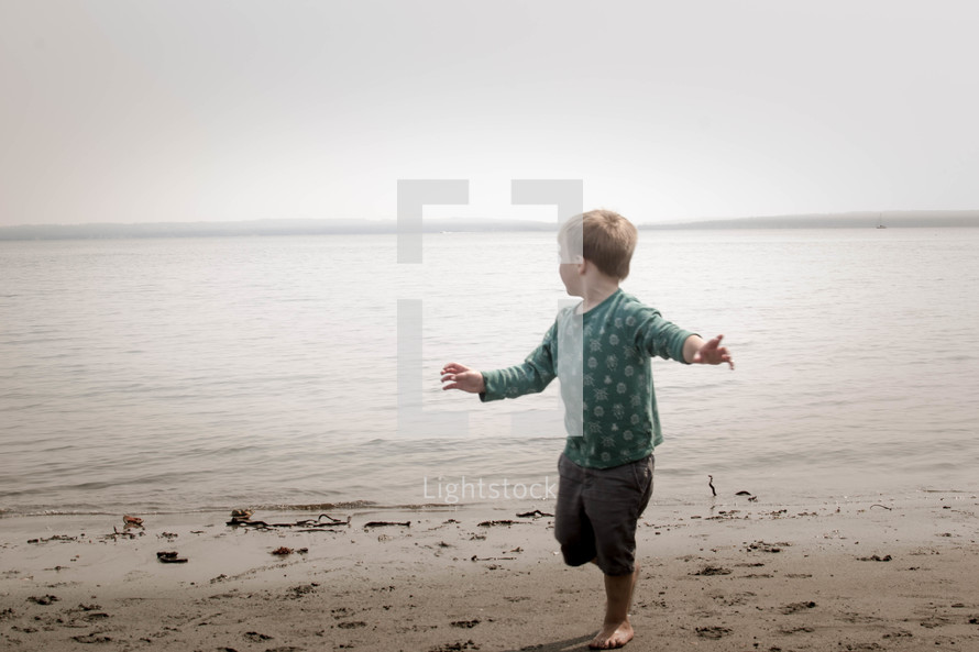 toddler running on a lake shore 